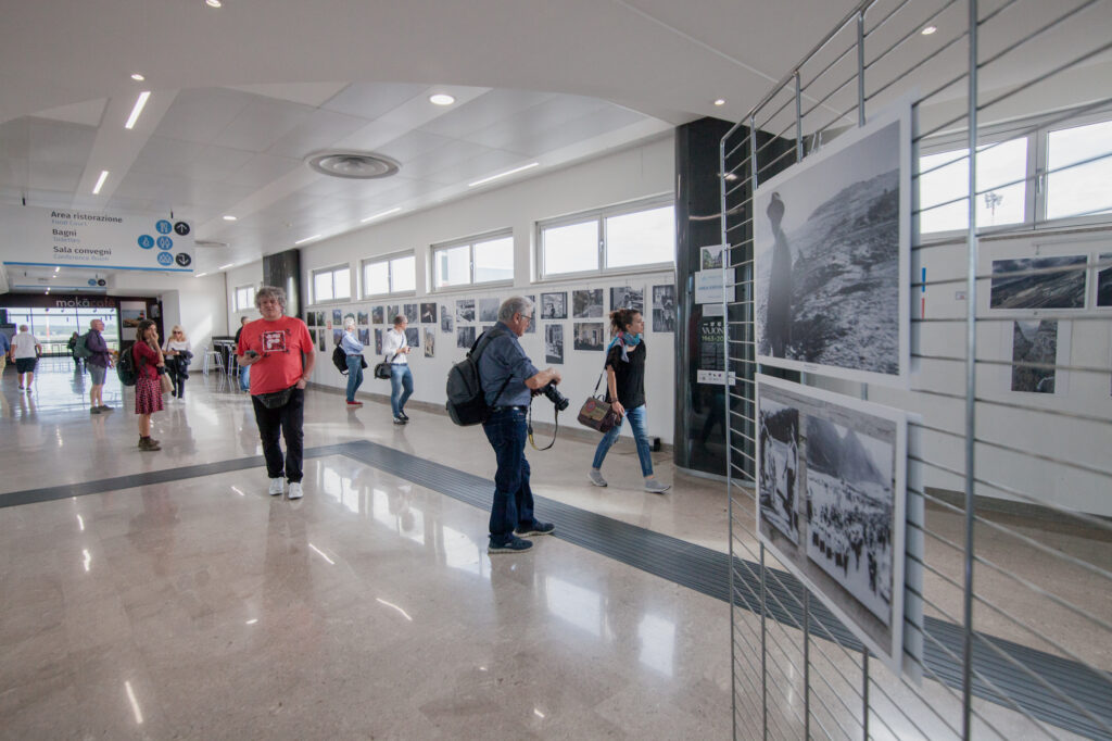 Persone che guardano una mostra fotografica all'aeroporto di Trieste