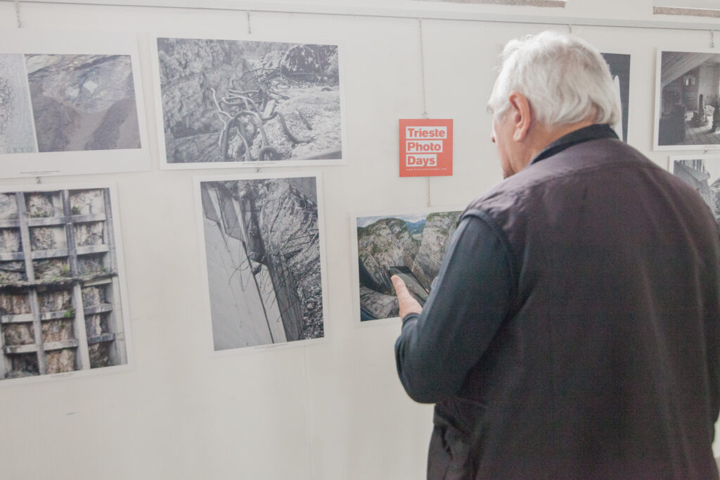 Signore anziano che guarda delle foto esposte in memoria della diga del Vajont